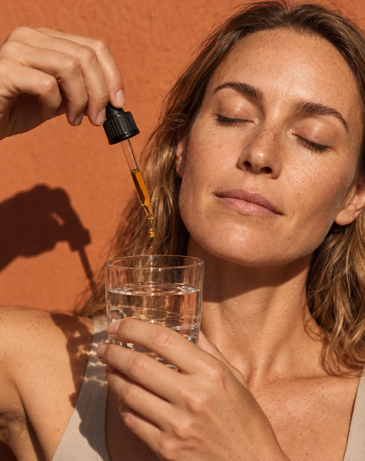 A drop falls into a glass of water in hard sun