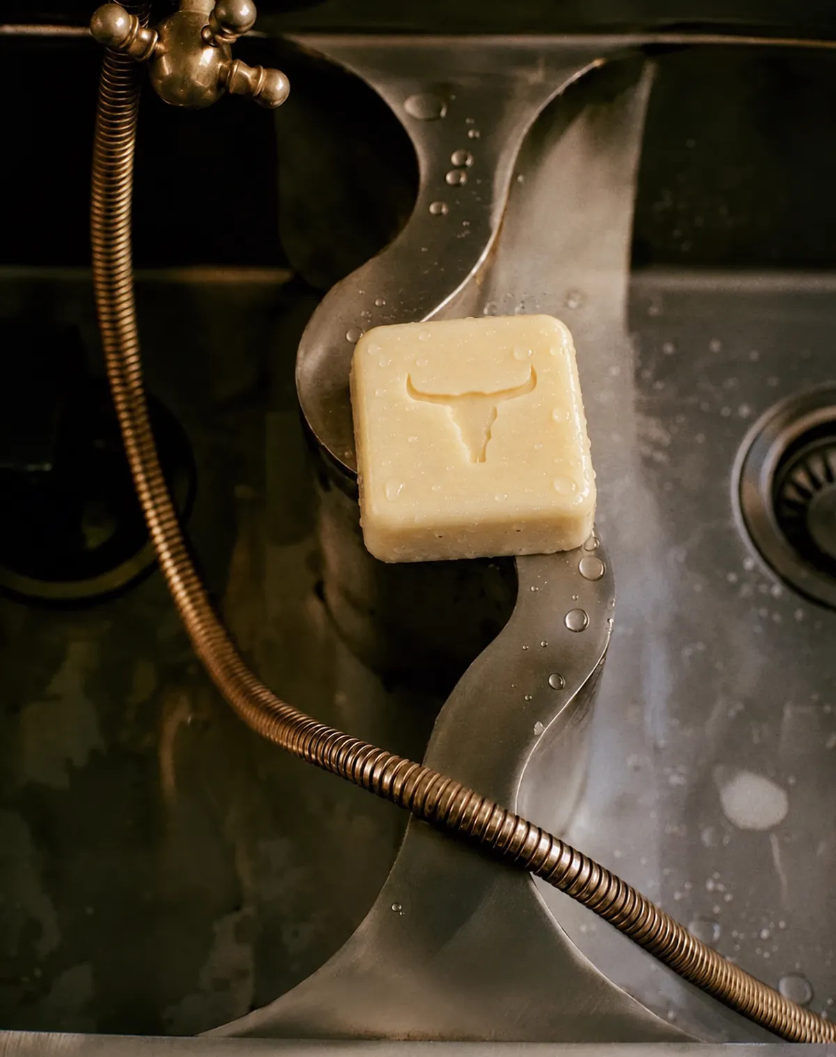A tallow soap bar on a wet brass sink